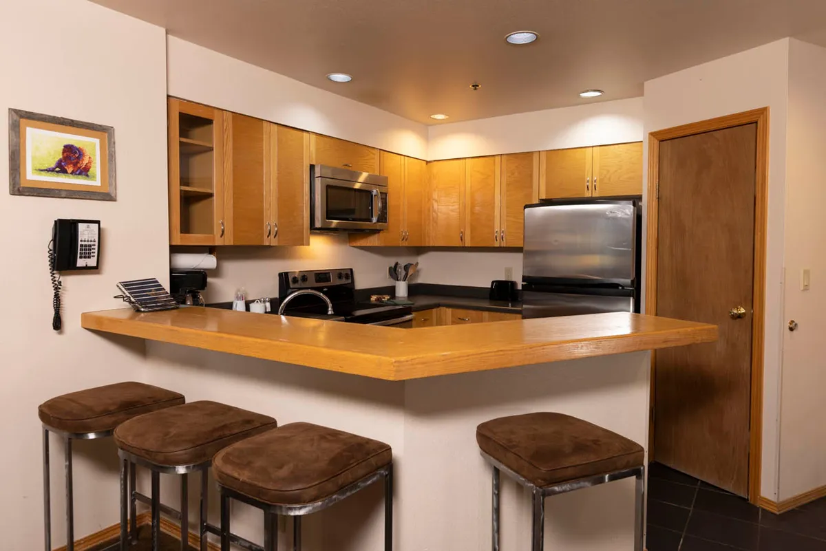 A welcoming kitchen with a central island, stools for seating, up-to-date appliances, and art on the wall. The layout encourages socializing during meal prep, with ample space for gathering and entertaining.